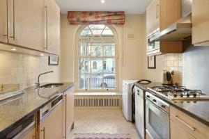 eine große Küche mit einem Waschbecken und einem Fenster in der Unterkunft Three Bedroom Apartment in Sloane Square in London