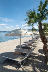 a row of lounge chairs and umbrellas on a beach at Grand Hotel Dino in Baveno