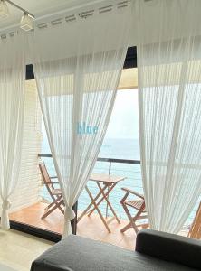 una sala de estar con cortinas blancas y vistas al océano. en El Salon, Nerja BLUEWATER VILLAS en Nerja