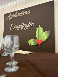 uma mesa com um copo de vinho e uma placa na parede em L’agrifoglio em Francavilla in Sinni