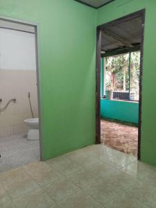 a bathroom with a toilet and a green wall at Grandma's House in Khao Sok National Park