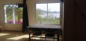 a table with chairs in front of a large window at Le repaire des pirates in Pietrosella