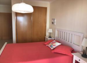 um quarto com uma cama vermelha e 2 almofadas vermelhas em Varandas Do Sol 2 em Portimão
