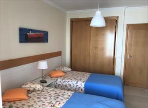 a bedroom with two beds and a lamp and a door at Varandas Do Sol 2 in Portimão