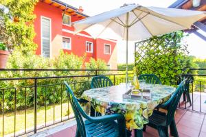 una mesa con sillas y una sombrilla en el balcón en Casa Irina, en Riva del Garda