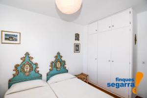 - une chambre avec 2 lits et un mur blanc dans l'établissement Sant Jordi 32, à Roda de Bará