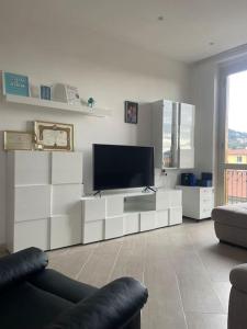 uma sala de estar com televisão e mobiliário branco em Casa vacanza Le Cinque Terre em La Spezia