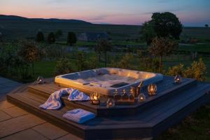 a jacuzzi tub on a deck with lights at Kipney Farmhouse - luxury hunting lodge in Perth