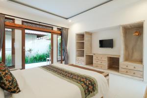 a bedroom with a large bed and a tv at Pondok Sebali Private Villa in Ubud