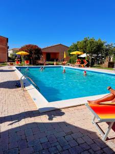 a swimming pool with people sitting in chairs and umbrellas at Podere Casalpiano in Campiglia Marittima