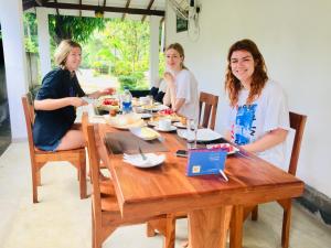 ハバラナにあるSwan Lake Habaranaの木製のテーブルの周りに座って食べ物を食べる三人の女性