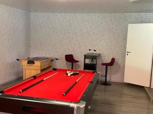 a red pool table in a room with two red chairs at Harmonie, an der Nordküste in Nordenham