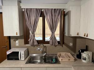 een keuken met een wastafel, een magnetron en een raam bij Elena maisonette by the sea in Kamena Vourla