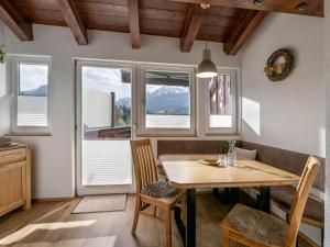 a dining room with a table and chairs and windows at Appartement Mayrl in Fieberbrunn