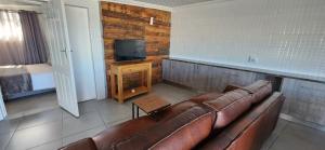ein Wohnzimmer mit einem Sofa und einem TV in der Unterkunft 12 on Krisant avenue in Van Riebeekhoogte