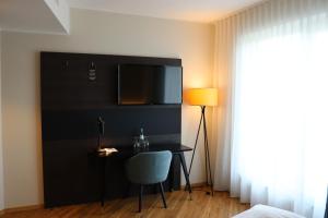 Habitación con escritorio y TV en la pared. en EINSTEIN Hotel am Römerpark en Andernach