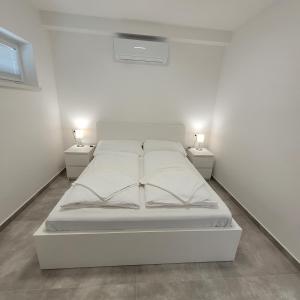 a white bed in a white room with two lamps at Szabadszél Apartmanok in Fonyód