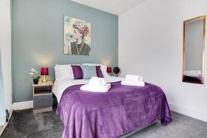 sypialnia z fioletowym łóżkiem i 2 ręcznikami w obiekcie Stylish 3-Bedroom Oasis in Darlington, Sleeps 5 w mieście Darlington