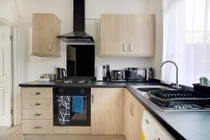 a kitchen with wooden cabinets and a black stove top oven at Stylish 3-Bedroom Oasis in Darlington, Sleeps 5 in Darlington