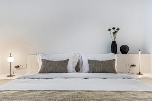 a white bedroom with a large white bed with pillows at Villa Paradeisos Karterados in Karterados