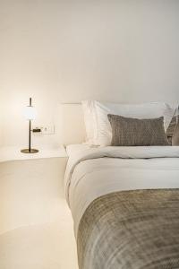 a white bedroom with a bed and a lamp at Villa Paradeisos Karterados in Karterados