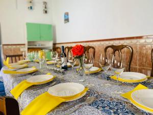 a table with yellow napkins and glasses and a red rose at Casa Antigua Estacion By Solymar Holiday in Málaga