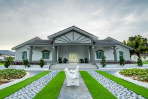 una casa con dos sillas blancas delante en Villa Dracaena Melaka - Private Pool, Hill View, 20 minutes to Town en Kampong Bukit Katil