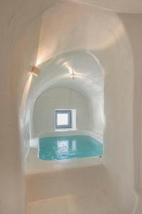una piscina en una habitación blanca con un arco en Villa Paradeisos Karterados, en Karterados