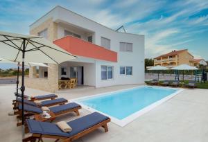 uma villa com uma piscina com cadeiras e um guarda-sol em Luxury residence Villa Astria em Knežević