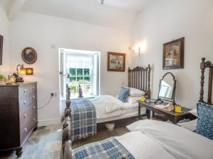 a bedroom with two beds and a dresser and a mirror at Ty Het in Llanfairpwllgwyngyll