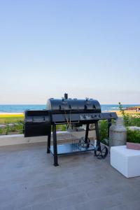 a bbq grill on a patio next to the ocean at Night Moon Villa JEBEL SIFA ,BF-109 in Muscat