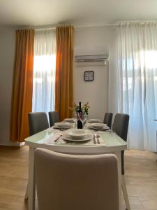 a dining room table with chairs and a white table with plates and flowers at Apartman Anđela Pula Centar in Pula +6 photos