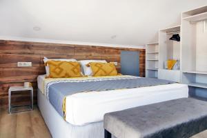 1 dormitorio con 1 cama grande y pared de madera en Okean Apartments, en Ierissos