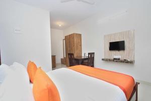um quarto com uma cama e uma televisão na parede em Hotel Royal Residence HSR Layout em Bangalore