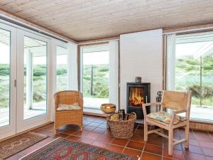 a living room with a fireplace and chairs and windows at 5 person holiday home in Hvide Sande in Hvide Sande