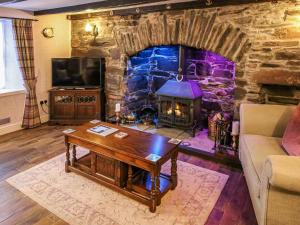 a living room with a stone fireplace and a wooden table at The Moorings in Garlieston