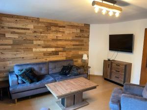 a living room with a blue couch and a wooden wall at Domek Bogusza in Kamionka Wielka