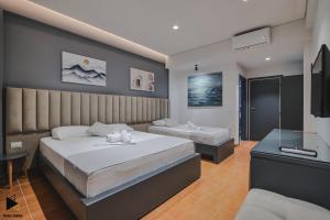 a bedroom with two beds and a flat screen tv at Hotel Alpha in Sarandë