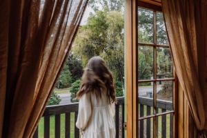 a little girl standing on a balcony looking out a window at The Quarters in Strahan