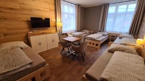 a room with three beds and a table and a tv at Penzion Pod Zámkem in Vizovice
