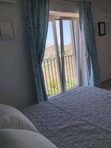 Un Capriccio - Ginepro في Aieta: غرفة نوم بسرير ونافذة مطلة