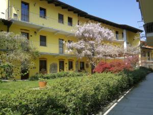 een geel gebouw met een bloeiende boom ervoor bij Agriturismo Tra Serra E Lago in Roppolo