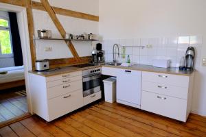 a kitchen with white appliances and a wooden floor at Gutshaus Thorstorf FeWo Poel in Thorstorf