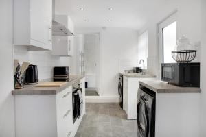 a kitchen with white cabinets and a microwave at Stunning 4-Bedroom, 2 Bathrooms in Sunderland in Sunderland
