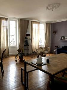 ein Wohnzimmer mit einem Tisch, Stühlen und Fenstern in der Unterkunft Apt plein de charme / centre ville / proche gare in Troyes
