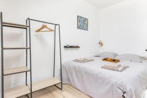 a white bedroom with a bed and a shelf at Gambetta 403 CahorsCityStay in Cahors