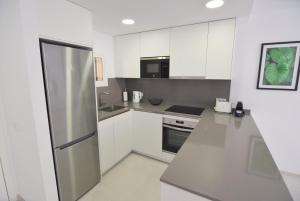 a kitchen with white cabinets and a stainless steel refrigerator at Las Mimosas in La Cala de Mijas