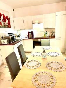 una cocina con mesa de madera con sillas y una cocina con armarios blancos. en "Apartament pod Śnieżką" uroczy apartament z kominkiem, en Karpacz