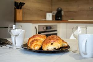 due croissant su un piatto con bicchieri da vino di Mende Sweet Home - Vue Cathédrale - Wifi - Centre ville a Mende