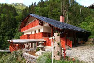 ein Haus mit schwarzem Dach und roter Ausstattung in der Unterkunft Guest House and Museum Firšt in Solčava